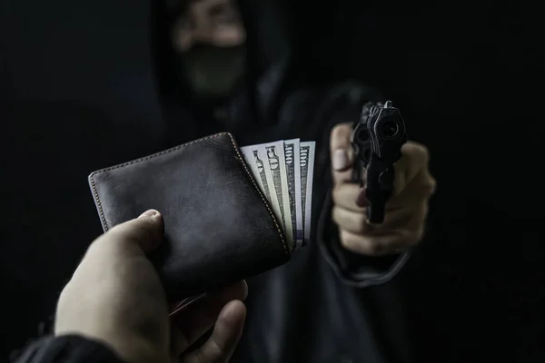 人的手伸出手去拿钱包给持枪抢劫犯 — 图库照片