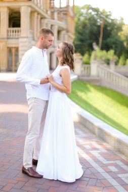 Mutlu gelin ve damat el ele tutuşup dışarıda duruyor..