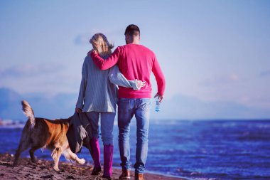 Köpekli çift, sonbahar günü sahilde eğleniyor.