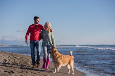 Köpekli çift, sonbahar günü sahilde eğleniyor.