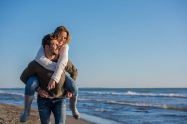 Çiftler güneşli bir sonbahar gününde kumsalda eğleniyorlar.