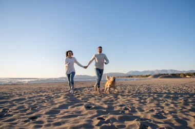 Köpekli çift, sonbahar günü sahilde eğleniyor.