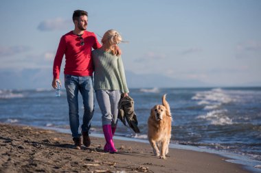Köpekli çift, sonbahar günü sahilde eğleniyor.