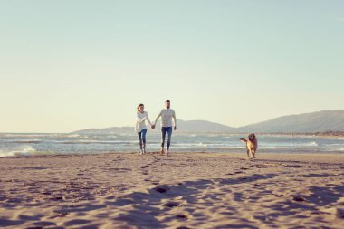 Köpekli çift, sonbahar günü sahilde eğleniyor.