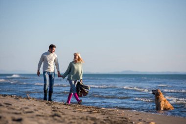Köpekli çift, sonbahar günü sahilde eğleniyor.