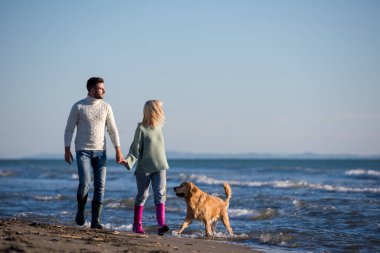 Köpekli çift, sonbahar günü sahilde eğleniyor.
