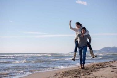 Çiftler güneşli bir sonbahar gününde kumsalda eğleniyorlar.