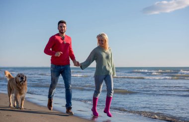 Köpekli çift, sonbahar günü sahilde eğleniyor.