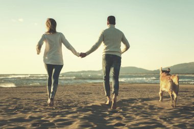 Köpekli çift, sonbahar günü sahilde eğleniyor.