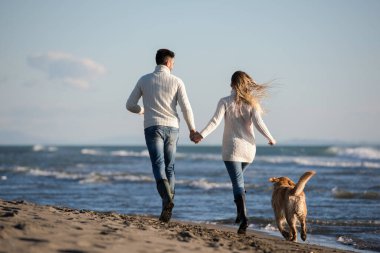 Köpekli çift, sonbahar günü sahilde eğleniyor.