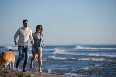Köpekli çift, sonbahar günü sahilde eğleniyor.