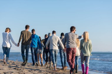 Sonbahar günü plajda koşan bir grup arkadaş