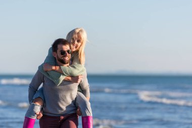 Çiftler güneşli bir sonbahar gününde kumsalda eğleniyorlar.