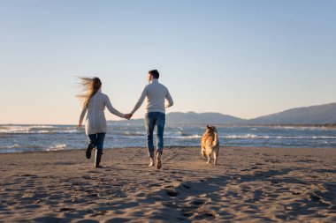 Köpekli çift, sonbahar günü sahilde eğleniyor.
