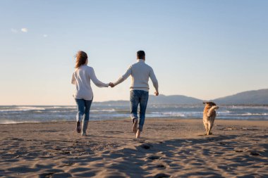 Köpekli çift, sonbahar günü sahilde eğleniyor.