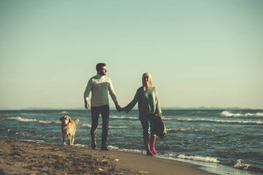 Köpekli çift, sonbahar günü sahilde eğleniyor.