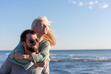 Çiftler güneşli bir sonbahar gününde kumsalda eğleniyorlar.