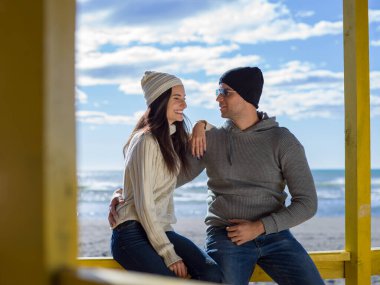 Çiftler konuşuyor ve sahilde eğleniyorlar.