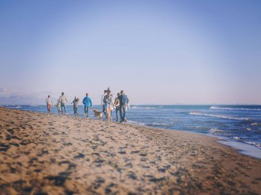 Sonbahar günü plajda koşan bir grup arkadaş