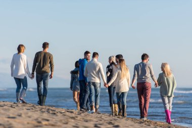 Sonbahar günü plajda koşan bir grup arkadaş