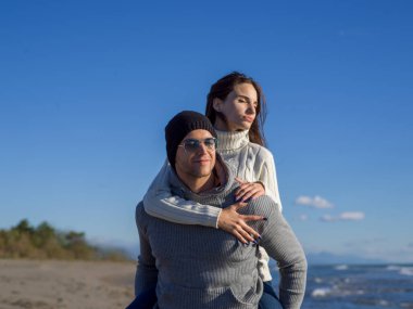 Çiftler güneşli bir sonbahar gününde kumsalda eğleniyorlar.