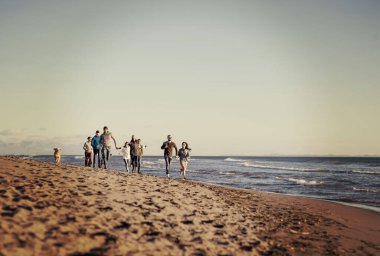 Sonbahar günü plajda koşan bir grup arkadaş