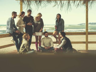 Bir grup arkadaş, sonbahar günü kumsalda eğleniyorlar.