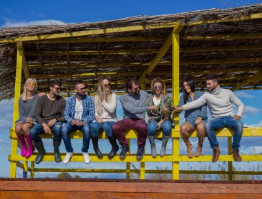 Bir grup arkadaş, sonbahar günü kumsalda eğleniyorlar.