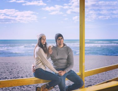 Çiftler konuşuyor ve sahilde eğleniyorlar.