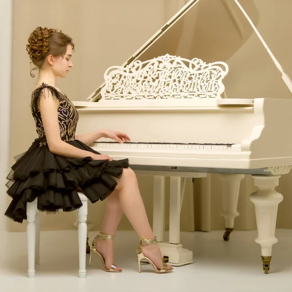 十代の女の子が白いグランドピアノで遊んでいる — ストック写真