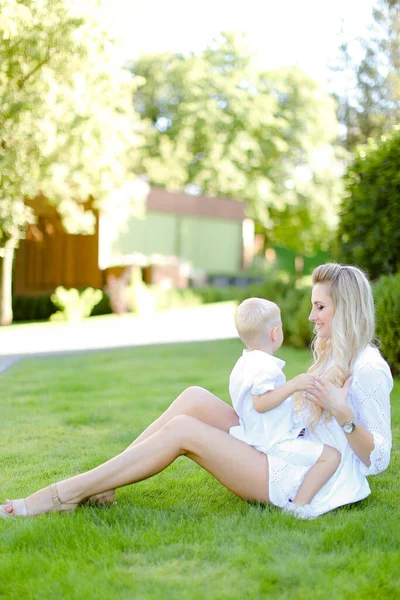 Młoda Szczęśliwa Matka Siedzi Małym Dzieckiem Trawie Podwórku — Zdjęcie stockowe