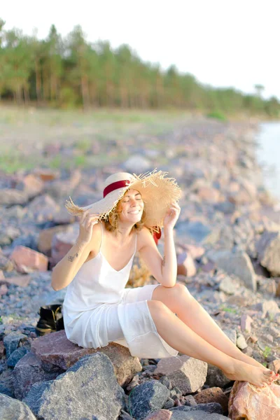 Junge Hübsche Frau Mit Hut Sitzt Auf Kiesstrand — Stockfoto