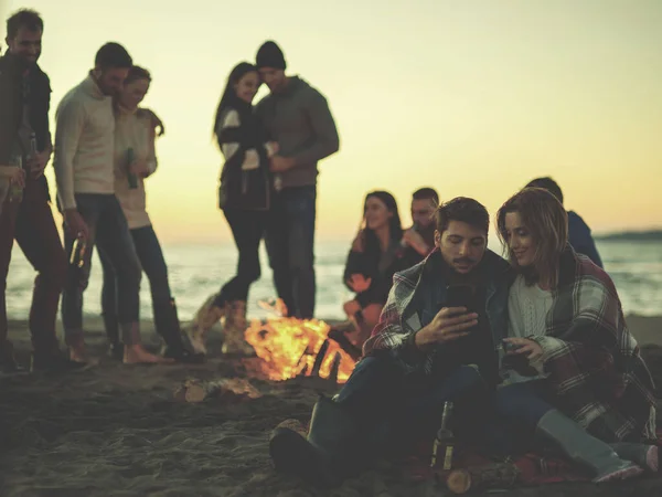 ビーチで友達と一緒にたき火を楽しむカップル — ストック写真