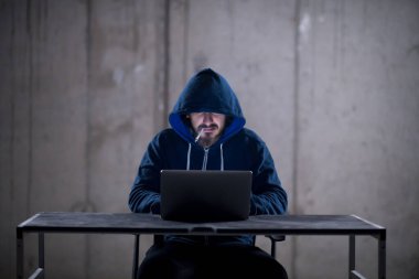 karanlık ofiste çalışırken dizüstü bilgisayar kullanarak genç hacker