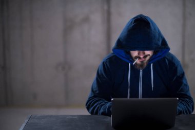 karanlık ofiste çalışırken dizüstü bilgisayar kullanarak genç hacker