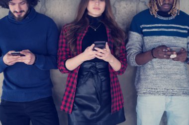 Beton duvarın önünde cep telefonu kullanan çok ırklı iş adamları.