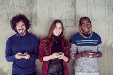 Beton duvarın önünde cep telefonu kullanan çok ırklı iş adamları.