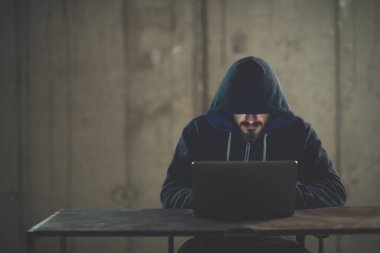 Karanlık ofiste çalışırken dizüstü bilgisayar kullanan yetenekli bir hacker.