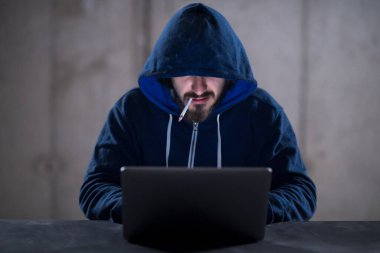 karanlık ofiste çalışırken dizüstü bilgisayar kullanarak genç hacker