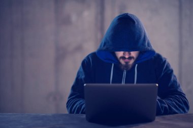 Karanlık ofiste çalışırken dizüstü bilgisayar kullanan yetenekli bir hacker.