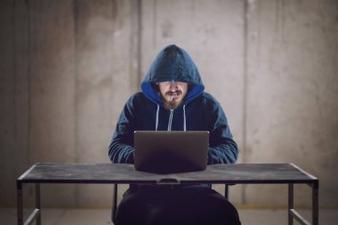 karanlık ofiste çalışırken dizüstü bilgisayar kullanarak genç hacker