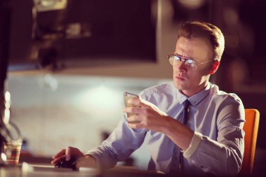 karanlık ofisinde cep telefonu kullanan adam