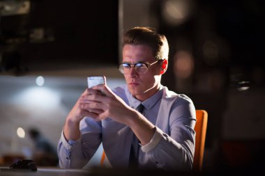 karanlık ofisinde cep telefonu kullanan adam