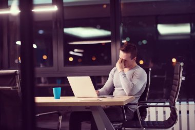 karanlık ofiste dizüstü bilgisayarda çalışan adam