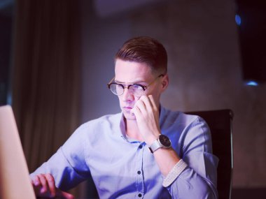 karanlık ofiste dizüstü bilgisayarda çalışan adam