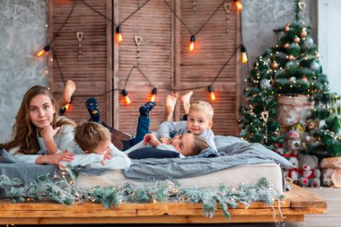 Mutlu çocuklar Noel sabahı Noel ağacının yanındaki yatakta eğleniyorlar.