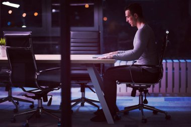 karanlık ofiste dizüstü bilgisayarda çalışan adam