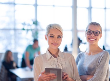 Güzel iş kadınları kullanarak Tablet içinde ofis binası konferans sırasında