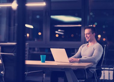 karanlık ofiste dizüstü bilgisayarda çalışan adam