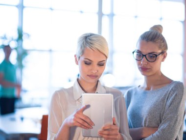 Güzel iş kadınları kullanarak Tablet içinde ofis binası konferans sırasında